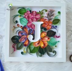 the letter j is made out of paper and decorated with flowers, leaves and butterflies