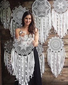 a woman standing in front of a wall with white crocheted doily hanging from it