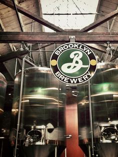 there is a sign that says brooklyn brewery on the side of some large metal tanks