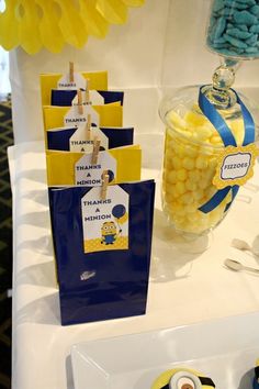 the table is set up with minion candy bags and place cards for guests to eat