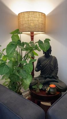 a buddha statue sitting on top of a wooden table next to a potted plant