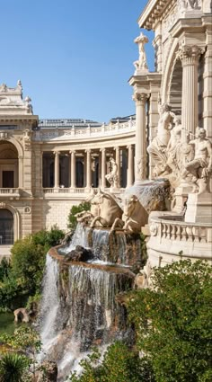 an ornate building with fountains and statues in the foreground