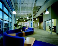 an office with blue couches and chairs in the middle of it, along with large windows