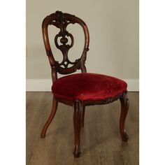 an antique chair with a red velvet seat cushion