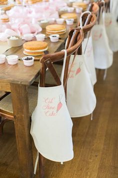 a table topped with lots of cupcakes on top of wooden chairs next to each other