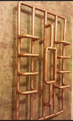 a metal rack with multiple pipes attached to it's sides, in front of a wall