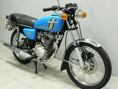 a blue and black motorcycle is parked in a room with tile flooring on the walls