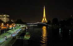 the eiffel tower is lit up at night with lights reflecting in the water