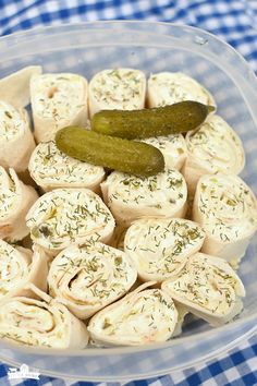 a bowl filled with rolls and pickles on top of a blue checkered table cloth