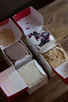 six different types of ice cream in boxes on a table with one missing the top