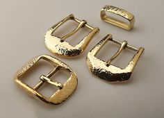 three gold buckles on a white surface