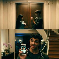 two people standing in front of a wooden door and one holding a cell phone to take a selfie