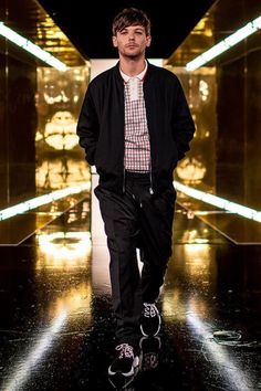 a man walking down a runway in a black jacket