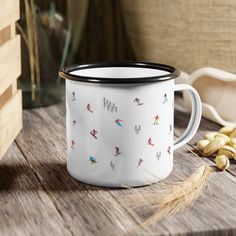 a white and black coffee mug sitting on top of a wooden table next to peanuts