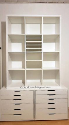 an empty white bookcase with drawers in the middle and shelves on each side for storage