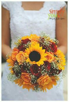 a woman holding a bouquet of sunflowers and roses