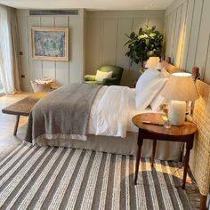 a large bed in a bedroom next to a table with a potted plant on it