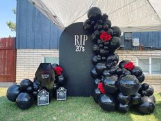 black balloons are arranged in the shape of a heart and flowers on display at an outdoor event