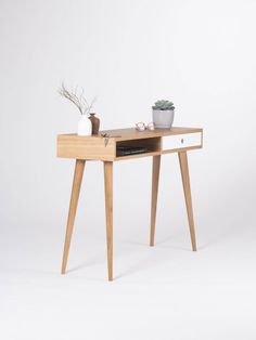 a wooden table with a potted plant sitting on it's top and drawers