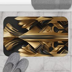 a bathroom rug with gold and black designs on it, next to a pair of slippers