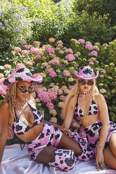 two women in matching outfits sitting on a blanket