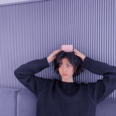 a young woman is holding her hair in front of her head while sitting on a couch