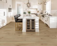 a large kitchen with white cabinets and wooden flooring, along with a center island in the middle