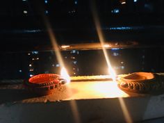 two lit candles sitting on top of a table in front of a window at night