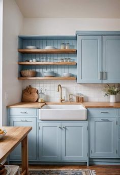 a kitchen with blue cabinets and wooden counter tops in the center is a white sink