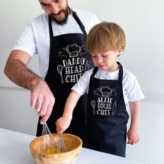 a father and son are cooking together in the kitchen while wearing aprons that read dad's happy chef