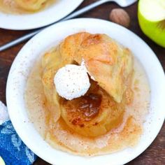 two white plates topped with apple pies on top of a wooden table next to sliced apples