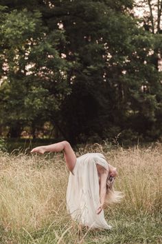 a woman in a white dress is standing on one leg and bending over her head