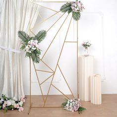 a wedding arch with flowers and greenery on the floor in front of a window