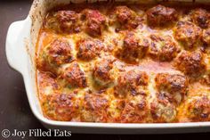 a casserole dish with meatballs and cheese in it on a black surface