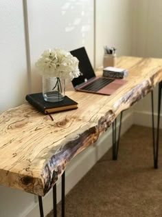 a wooden table topped with a laptop computer next to a flower vase on top of it