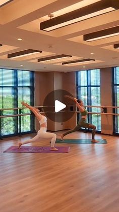 two people are doing yoga in an empty room with large windows and wooden flooring