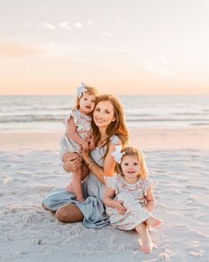 a mother and her two daughters on the beach at sunset