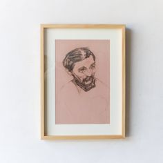 a framed drawing of a man's face on a white wall