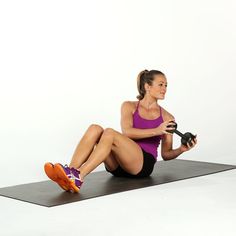 a woman sitting on a mat holding a pair of dumbbells with one leg in the air