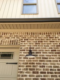 a brick building with two windows and a light on the outside wall next to a door