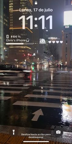 an image of a city street at night with buildings in the background and rain on the ground