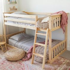 a bunk bed sitting next to a window in a room with rugs on the floor