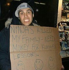 a man is holding a cardboard sign that says ninjas killed my family - need money for kinder lessons