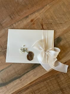 a white card with a button and ribbon tied around it on top of a wooden table