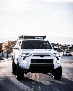 a white four - doored suv is driving down the road