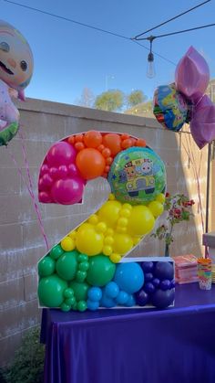 the number two balloon sculpture is made out of balloons and sits on top of a purple table