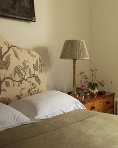 a bed with white sheets and pillows next to a lamp