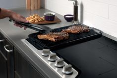 a person is grilling some meat on the stove top with tongs and seasonings