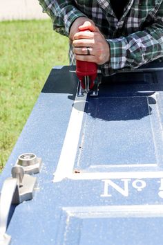 a man is using a drill to fix a piece of metal on the side of a table