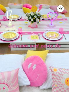 a table set up for a party with pink and yellow decorations, plates, napkins, and flowers